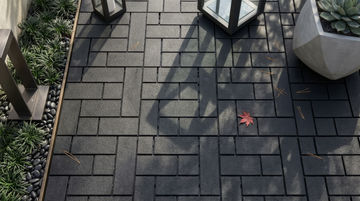 Black interlocking composite deck tiles shown beside outdoor planters and lanterns.