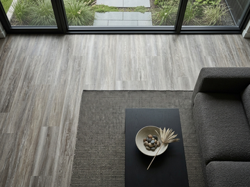 Blizzard SPC vinyl flooring, shown beside a dark sofa and coffee table.