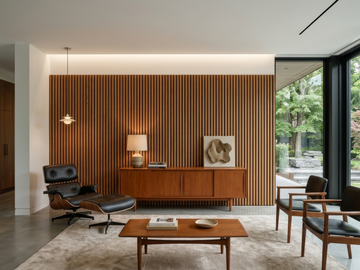 Vintage wood slat acoustic panels shown behind a sideboard in a living room with lounge chairs.
